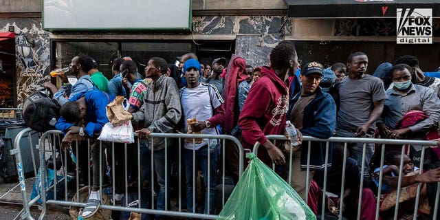 Migrants sit on the sidewalk in Manhattan