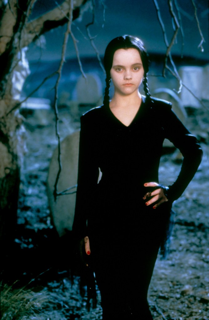 Wednesday Addams, played by Christina Ricci, poses with a serious face in a graveyard. 