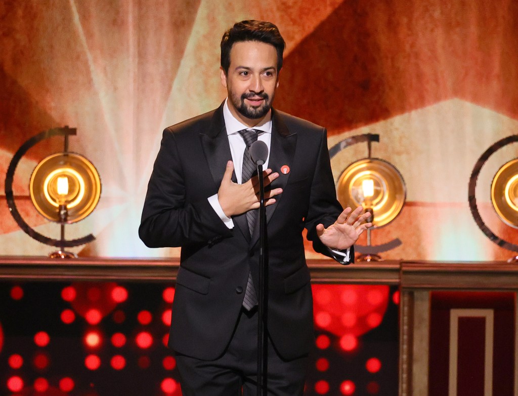 Lin-Manuel Miranda on stage in a suit.