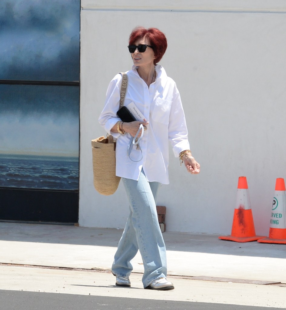 Photo of Sharon Osbourne walking in white shirt and jeans. 