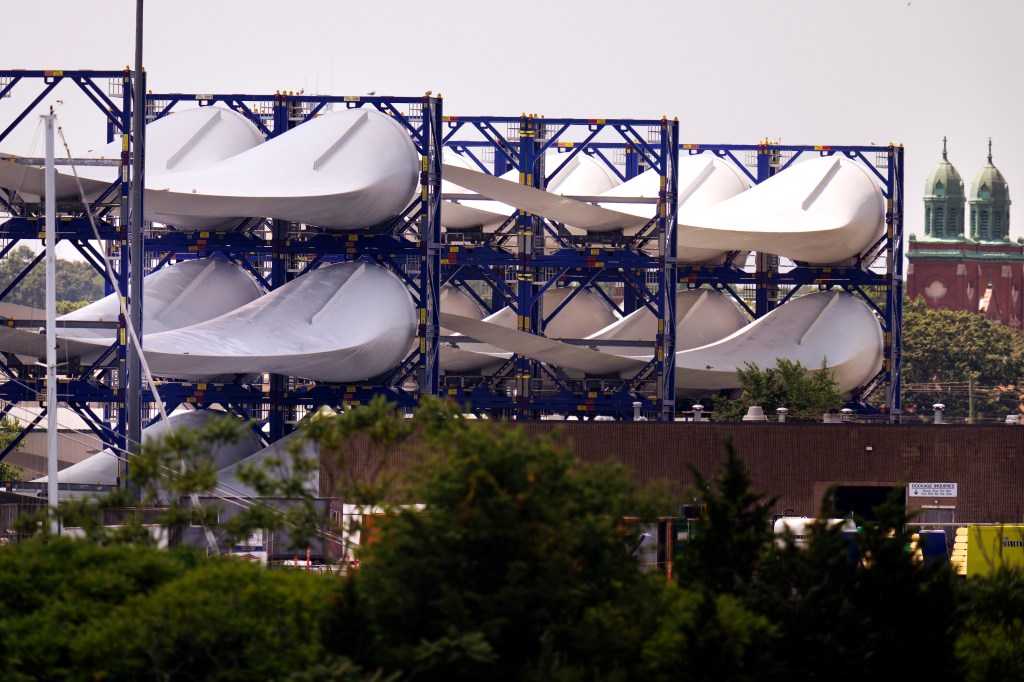 Giant wind turbine blades for the Vineyard Winds project are stacked on racks in the harbor, Tuesday, July 11, 2023