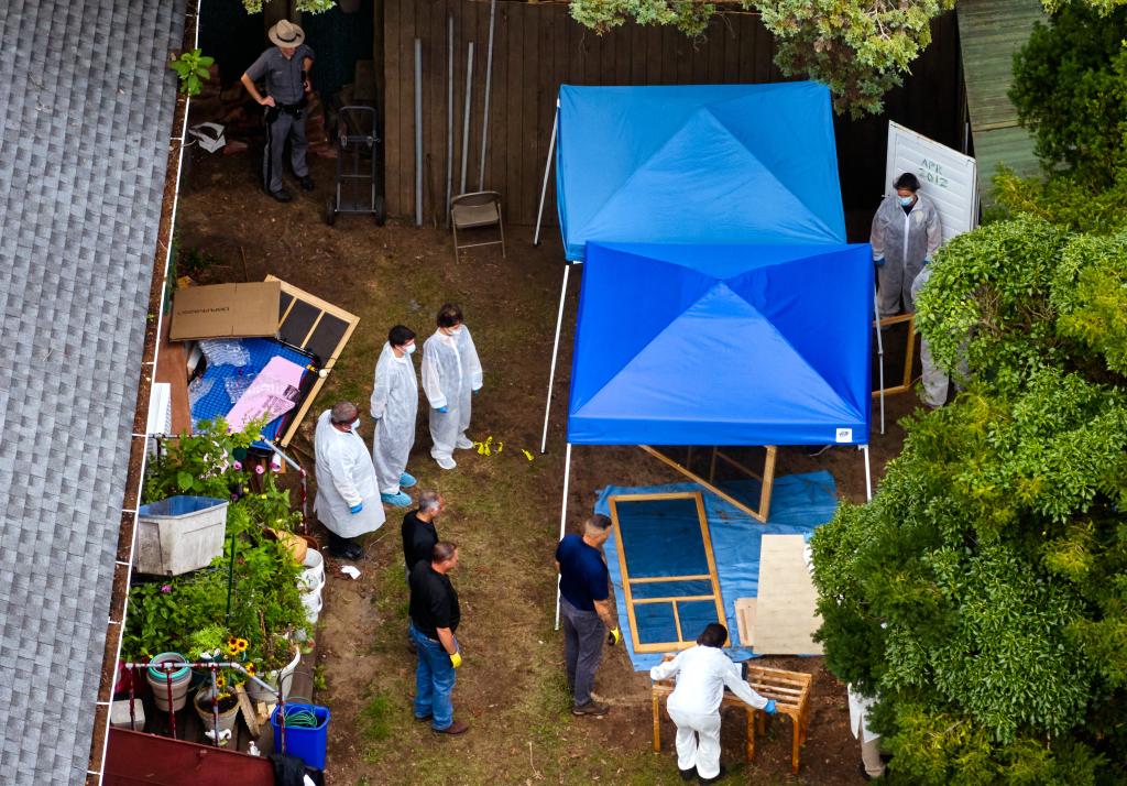 Crime scene investigators collect and document evidence from a shed in the backyard.