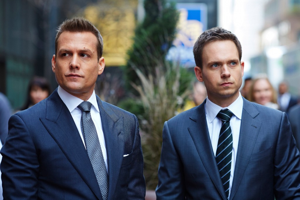Harvey and Mike in a later season of "Suits." They're standing side-by-side outside but are looking in different directions. They look like they're angry at each other.