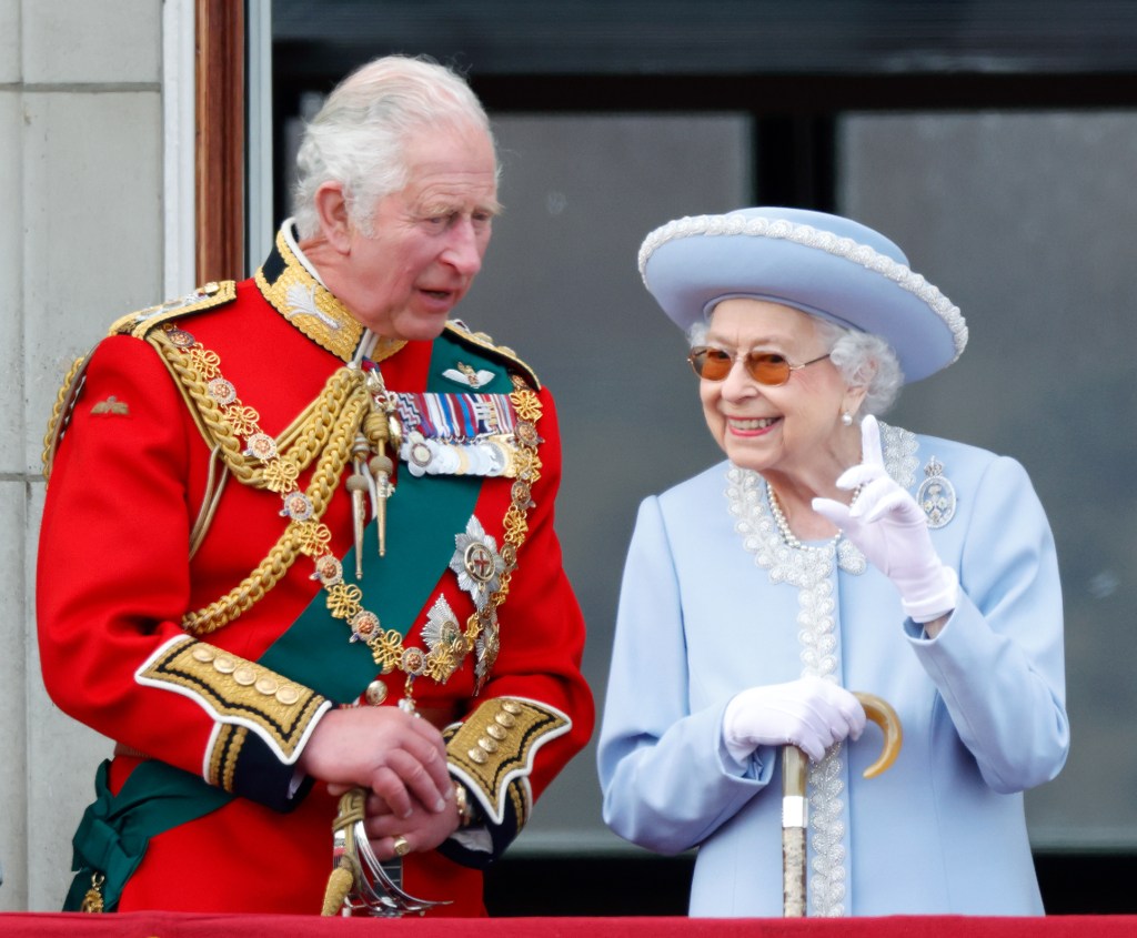 Queen Elizabeth standing with her son, King Charles, on the balcony of Buckingham Palace. 