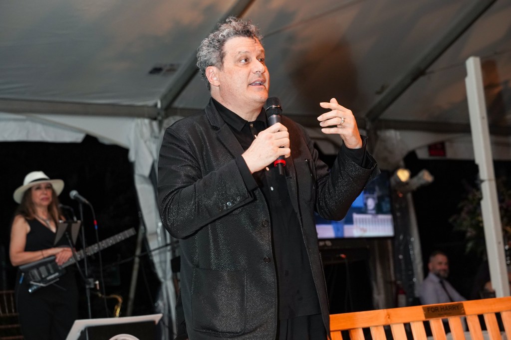 Photo of Isaac Mizrahi speaking into a microphone at an event. 