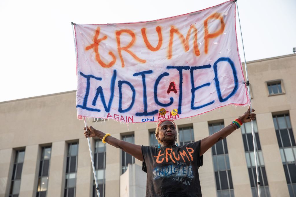 A woman holds a banner about Trump's indictment in front of E. Barrett Prettyman United States Courthouse on Aug. 2, 2023.