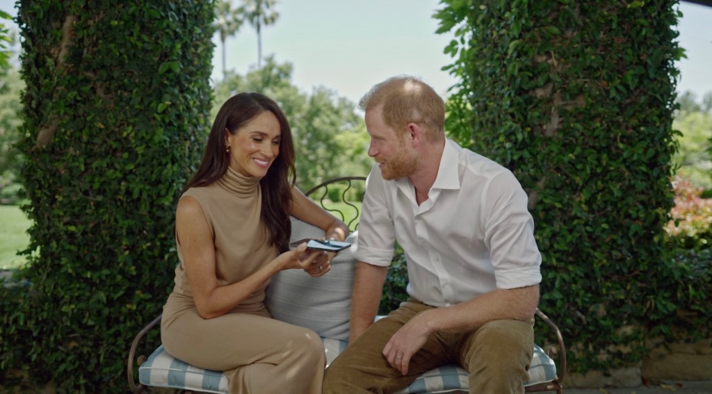 Meghan Markle and Harry sit on a couch outside. 