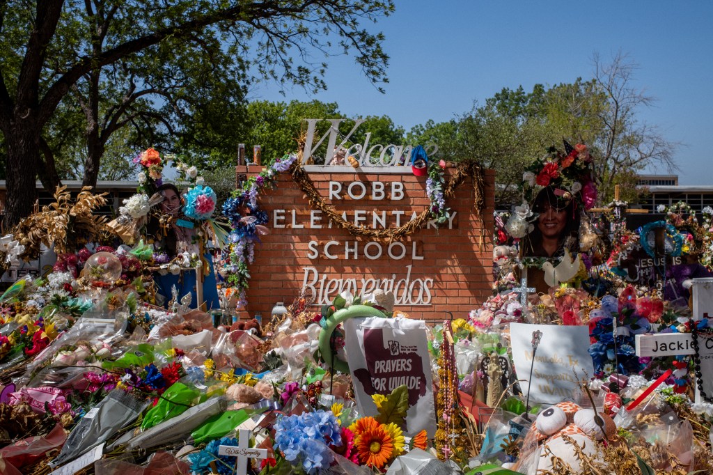 The Robb Elementary School sign is seen covered in flowers and gifts on June 17, 2022 in Uvalde, Texas. 