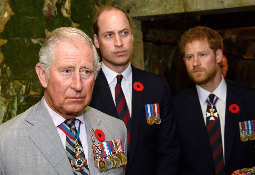 Photo of King Charles and Prince William and Prince Harry standing behind him. 