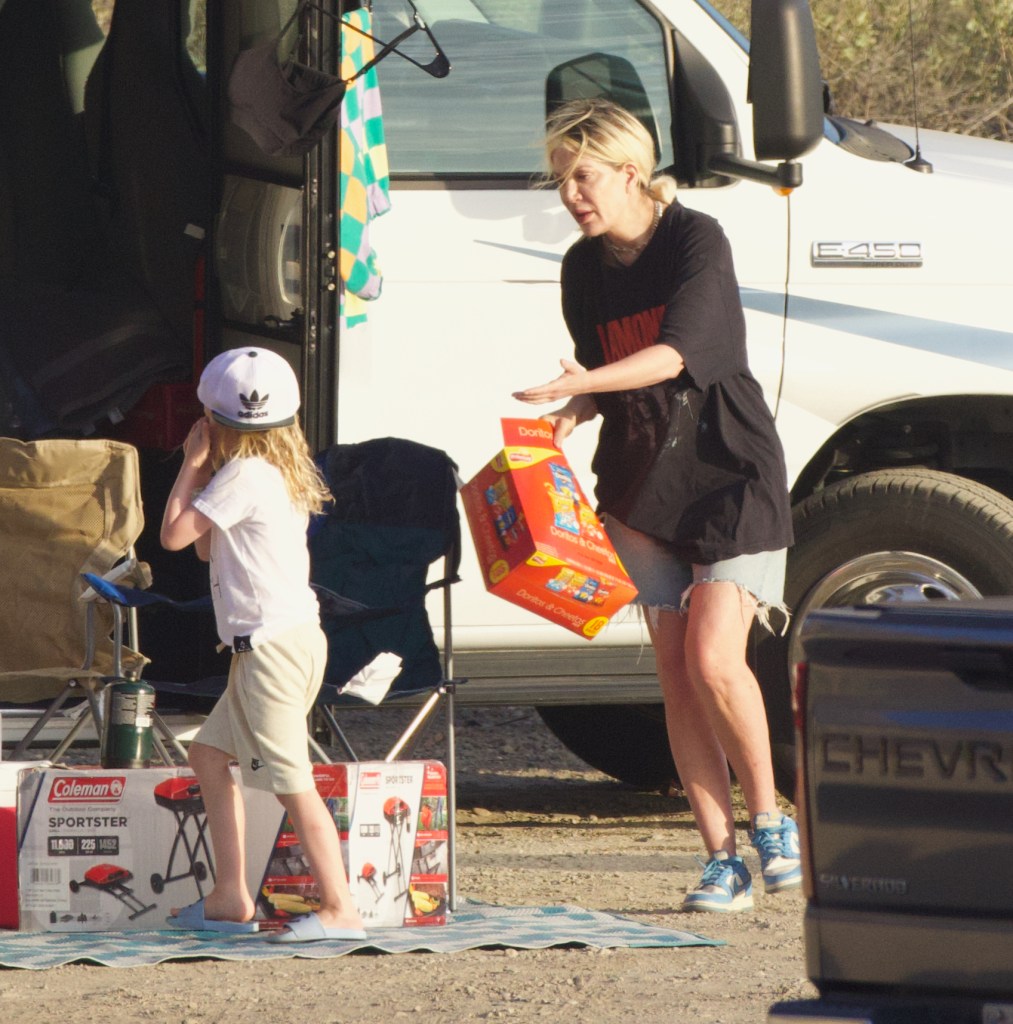 Spelling interacting with a young child while holding an assorted box of chip bags. 