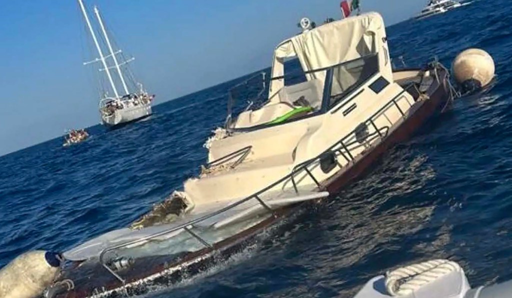 The remains of the 29-foot motorboat with the 130-foot sailing yacht in the background. The sailboat was stationary during the wreck, and witnesses said the motorboat was speeding as it passed before suddenly turning and colliding