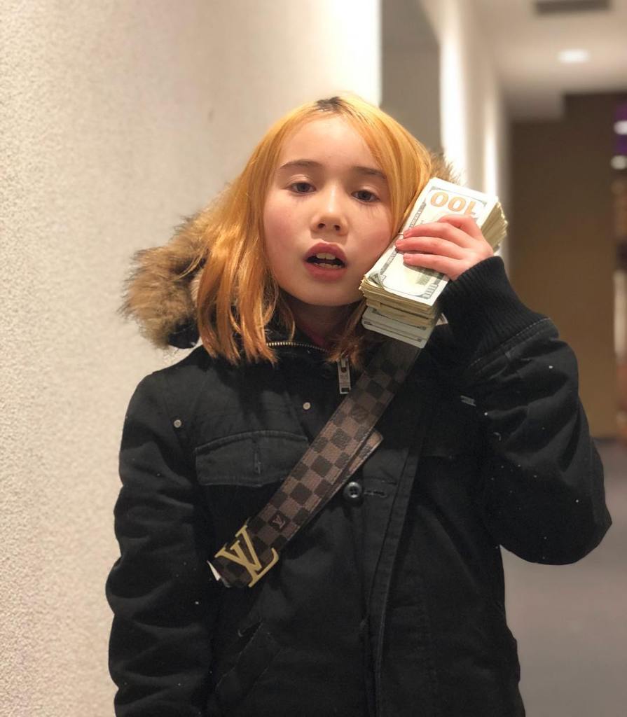 Lil Tay, 14, with a wad of cash to her ear. 