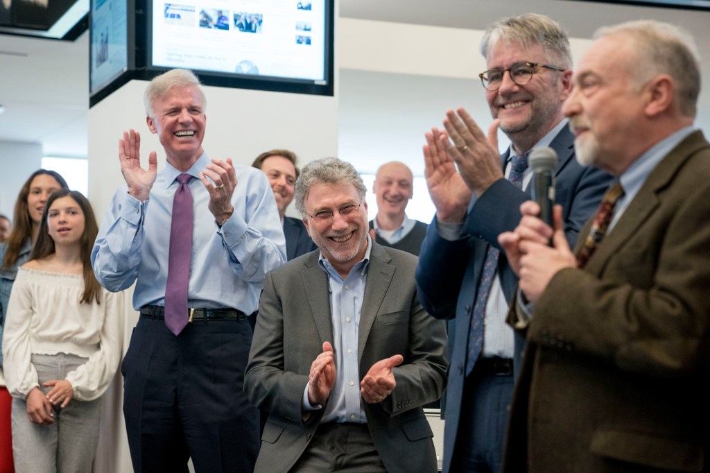 Washington Post Publisher Fred Ryan, foreground from left, Executive Editor Marty Baron, and National Security Editor Peter Finn, applaud as investigative reporter Tom Hamburger speaks to the newsroom