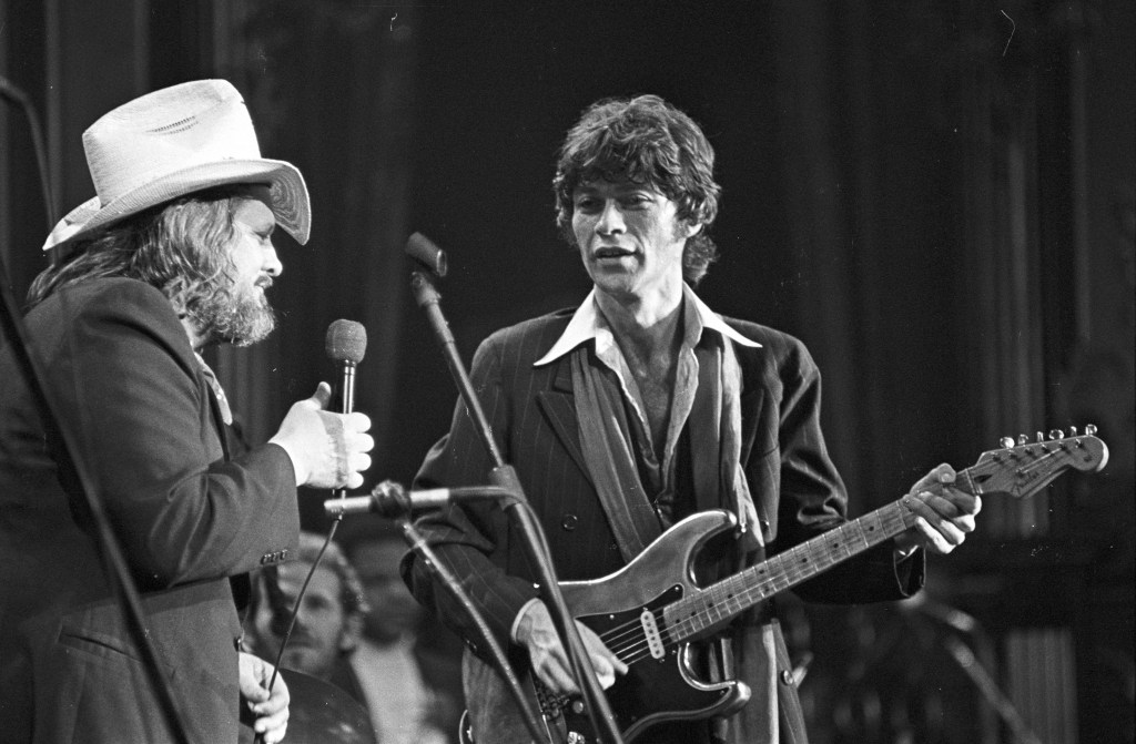 Ronnie Hawkins and Robbie Robertson (playing a Fender Stratocaster electric guitar) perform on stage at The Band's 'The Last Waltz' concert at Winterland Ballroom in 1976 in San Francisco.