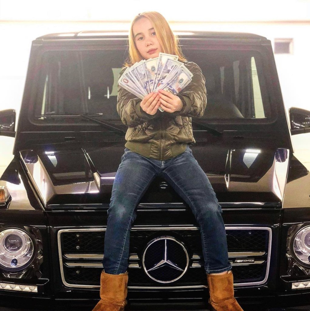 Lil Tay, 14, sitting on a Mercedes-Benz and holding money. 