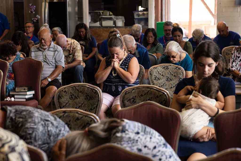 Survivors and churchgoers pray during a Sunday church service