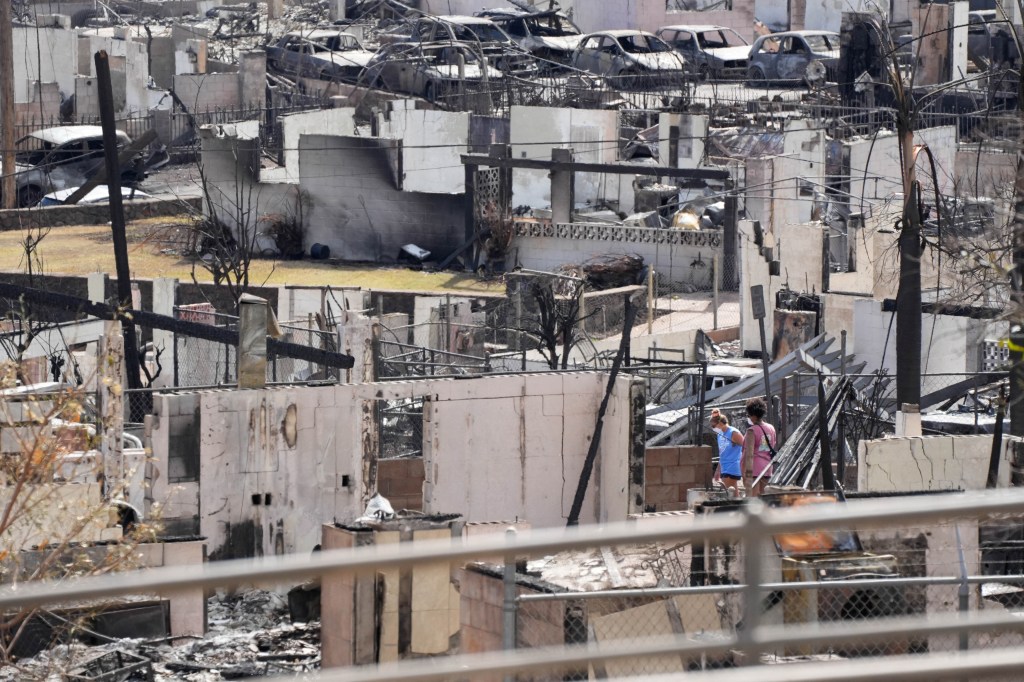 Two people examine a burned house after an inferno destroyed much of the historic Maui resort town of Lahaina, Hawaii.