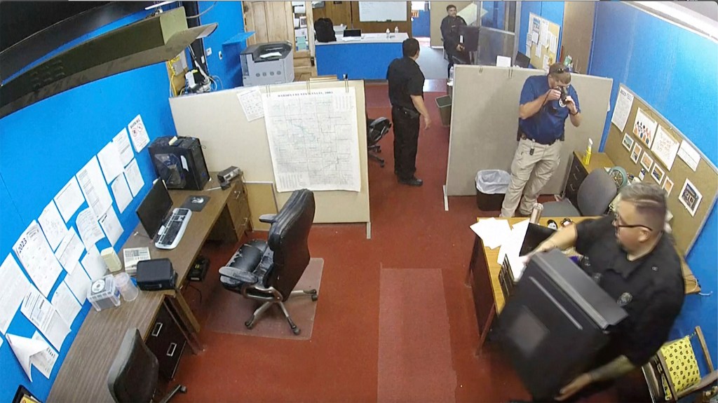 A newspaper office with police removing items and taking photos.