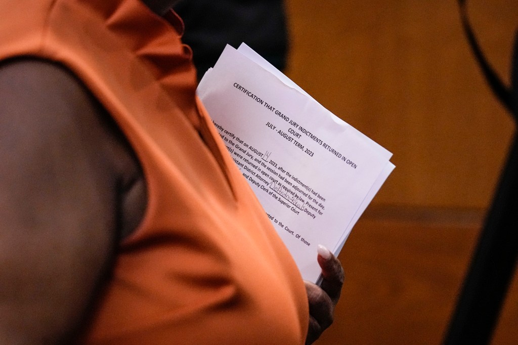 County Clerk Che Alexander departs the courtroom holding paperwork.