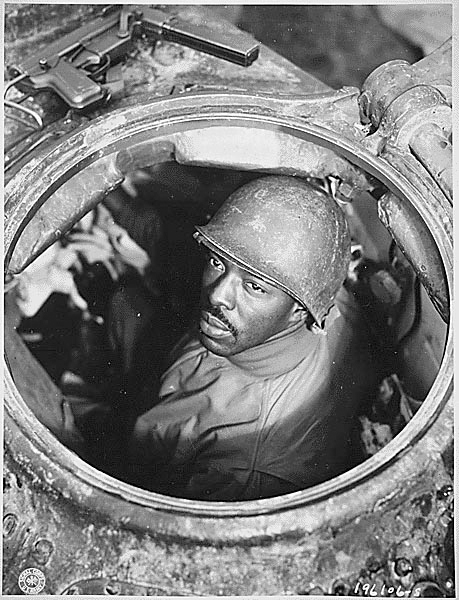 Corporal Carlton Chapman of the 761st Tank Battalion, a machine gunner, peers out of a Sherman tank hatch in Nancy, France during World War II.