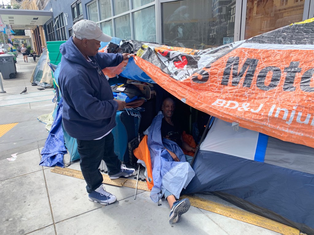 JJ Smith, a long time resident of the Tenderloin District in San Francisco, California, checks in on a homeless man on the street in the Tenderloin District on Thursday, August 17, 2023.