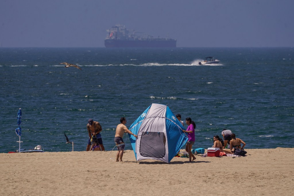 Beach goers hold onto their tent in California as the state anticipates its first tropical storm in nearly a century. 