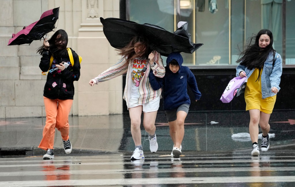 Pedestrians attempting to walk through the heavy rain on  Hollywood Boulevard in Los Angeles.