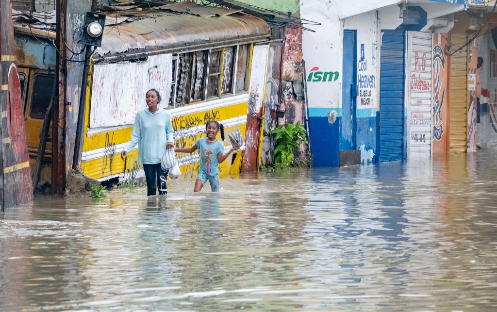 People walk through a street flooded by the rains of Tropical Storm Franklin in Santo Domingo, Dominican Republic, Tuesday.
