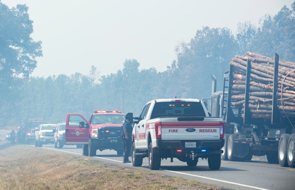 Timber trucks and fire personnel occupy Highway 27 while helping fight a wildfire.