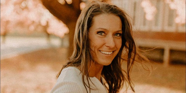 Rebecca Bliefnick smiles in sepia tone photo in front of large tree