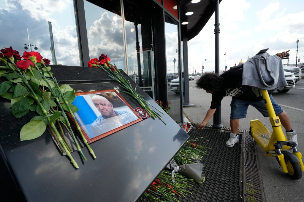 A man places flowers at an informal memorial at a cafe owned by Prigozhin in St. Petersburg, Russia, on Aug. 25, 2023.