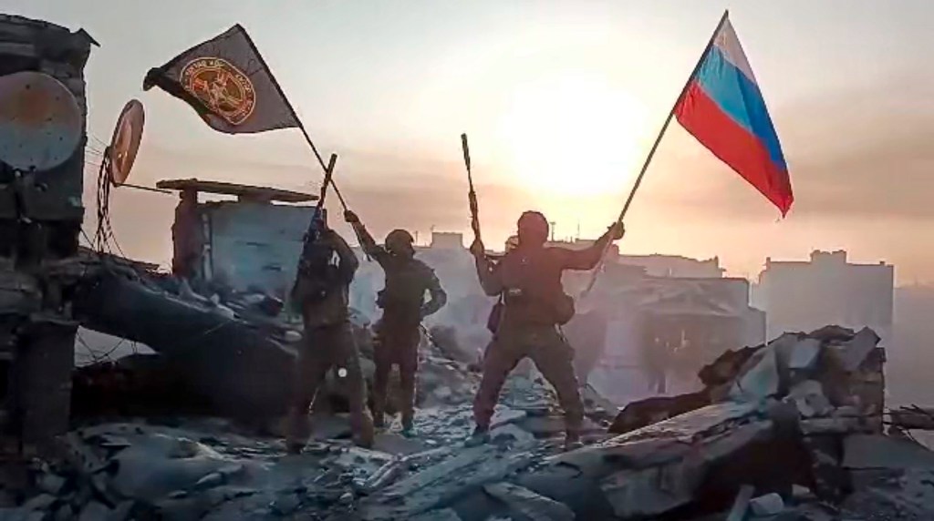 Wagner Group military company members wave a Russian and Wagner flag atop a damaged building in Bakhmut, Ukraine on May 20, 2023.