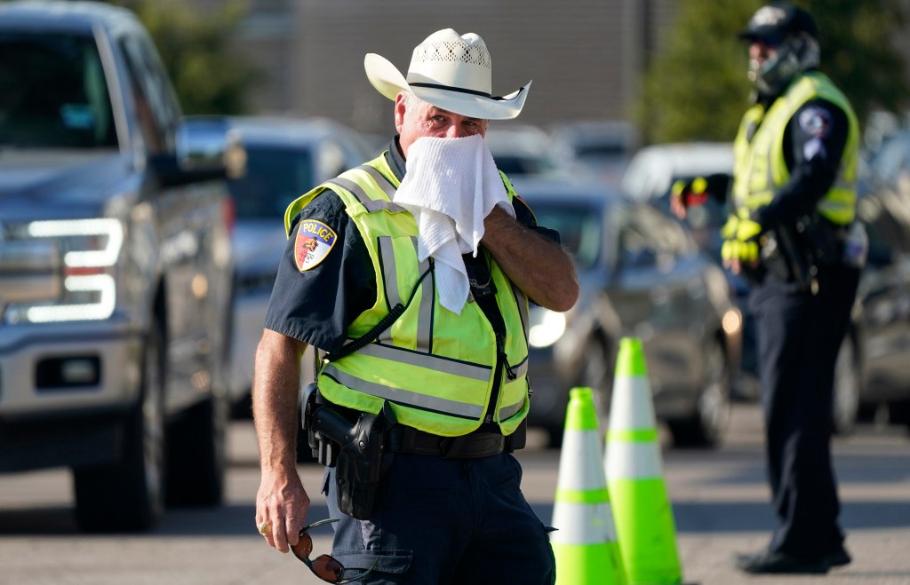 An Arlington police officer cools himself off with a wet towel while directing traffic on Aug. 19.
