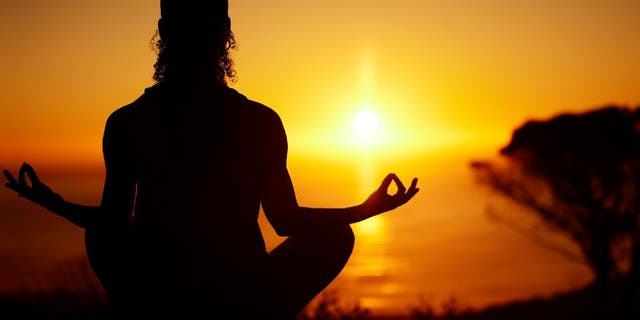 Woman meditates at sunset