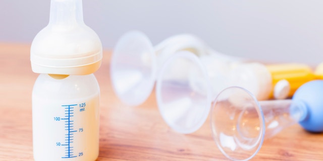 Baby bottle with milk and a measuring scale, manual breast pump, mothers breast milk is the most healthy food for newborn baby. Objects standing in a row. Selective focus