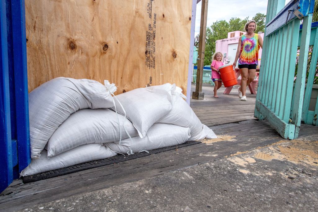 People in Cedar Key carry their belongings next to a building covered with plywood as the town prepares for the hurricane.  