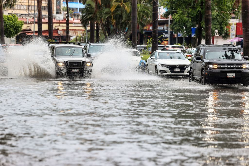 Cars move on a flooded street due to heavy rains in the resort of Acapulco, Guerrero state, Mexico, on Aug. 16, 2023.