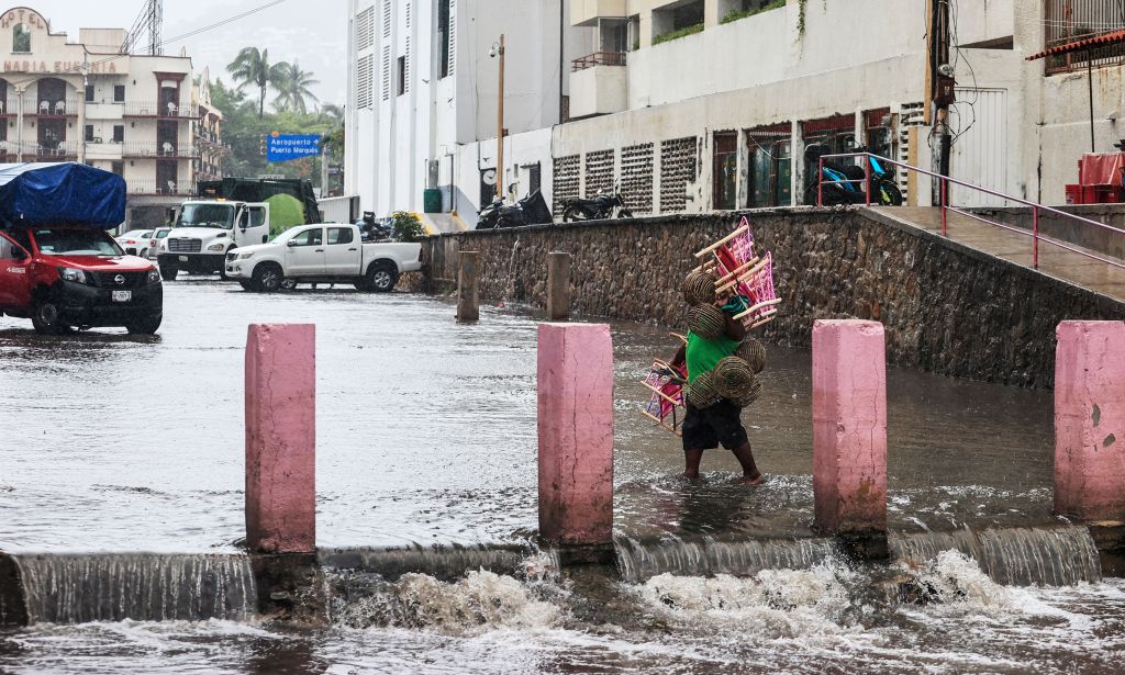 A person walks through a flooded street due to heavy rains in the resort of Acapulco, Guerrero state, Mexico, on Aug. 16, 2023. 