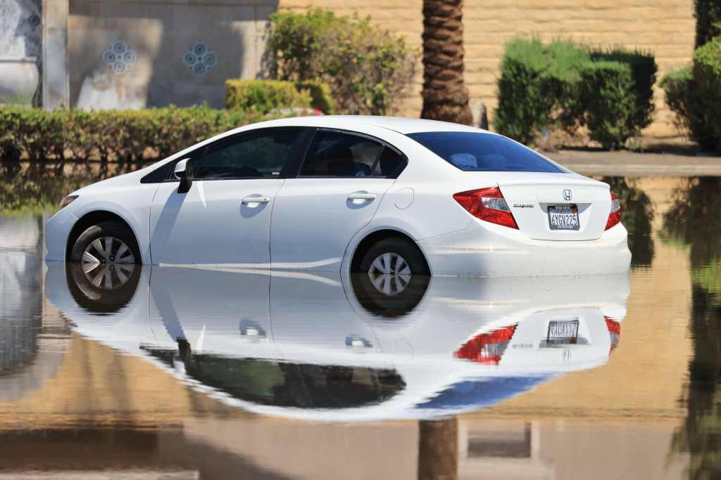 A car is pictured in a flooded street following heavy rains from Tropical Storm Hilary in Cathedral City, California. 