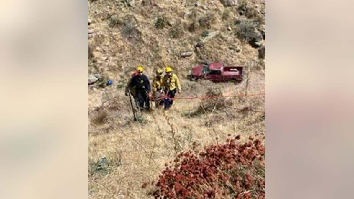 rescuers helping injured driver up hill