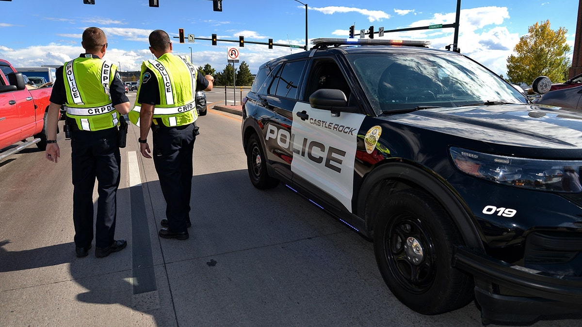 Castle Rock Police Officers next to a police car on the street by an intersection