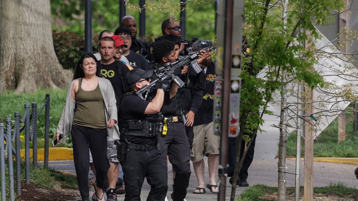 D.C. police with guns drawn escort people away from the scene of a shooting