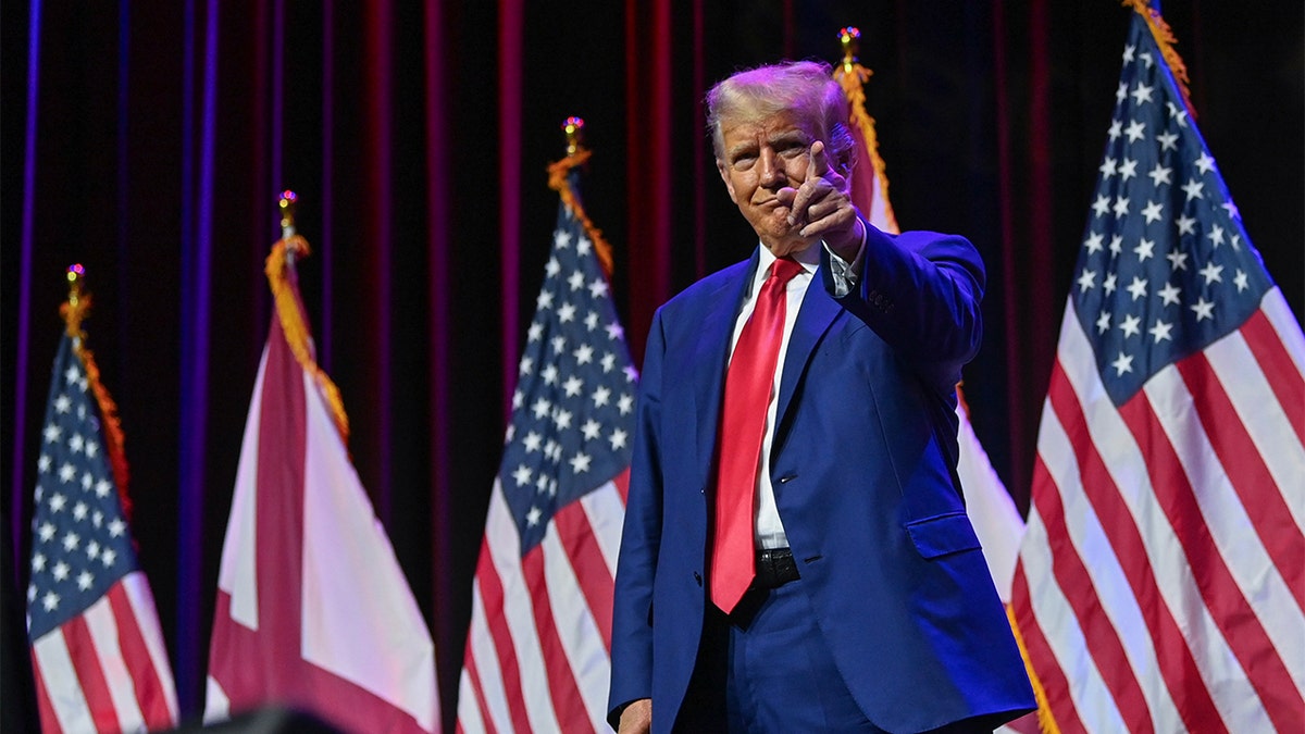 Former President Donald Trump on stage at an event pointing to the crowd