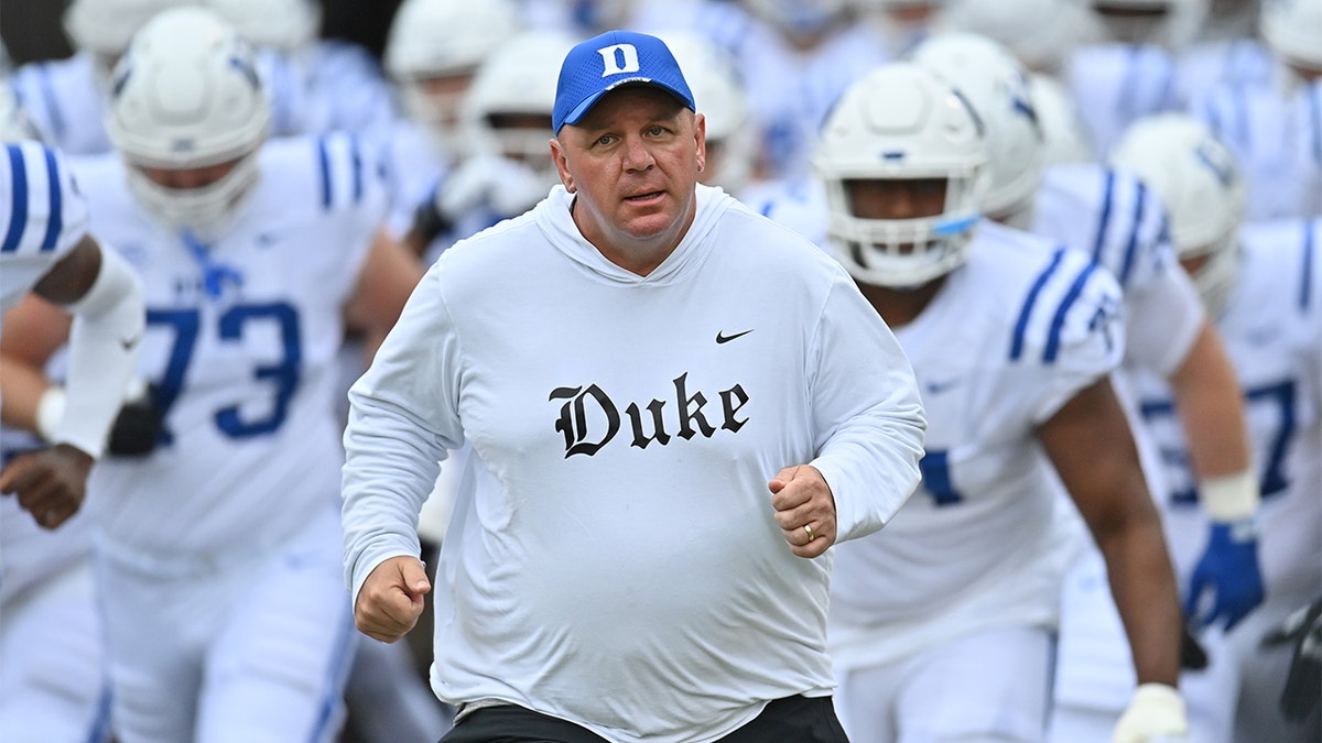 Mike Elko runs onto the field