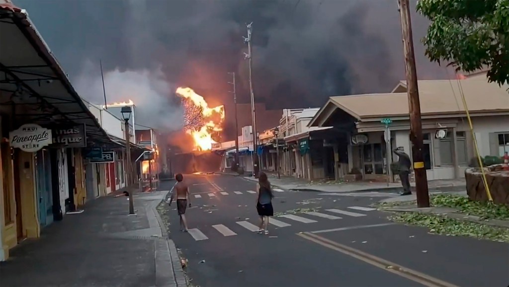 People watch as smoke and flames fill the air from raging wildfires on Front Street in downtown Lahaina, Maui on Tuesday, Aug. 8, 2023.