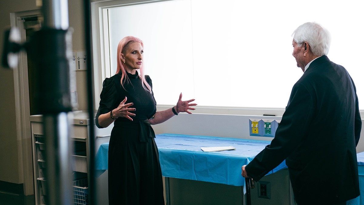 Alina Burroughs talking to a man next to a blue table