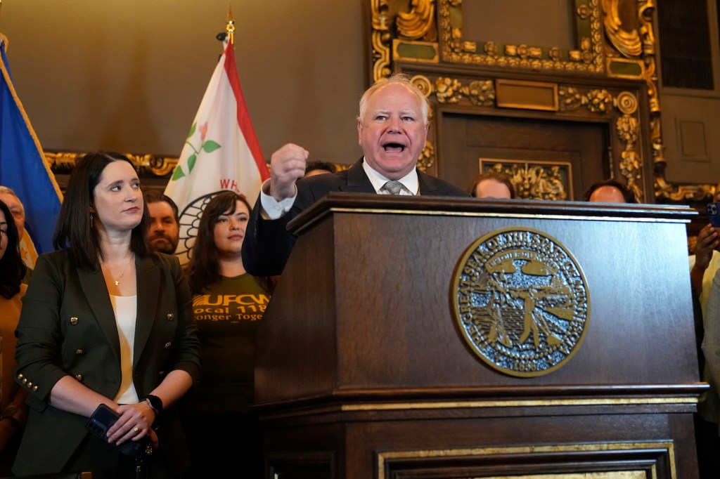 Minnesota Gov. Tim Walz, middle, speaks to the media before signing a bill to legalize recreational marijuana for people over the age of 21, May 30, 2023, in St. Paul, Minn.