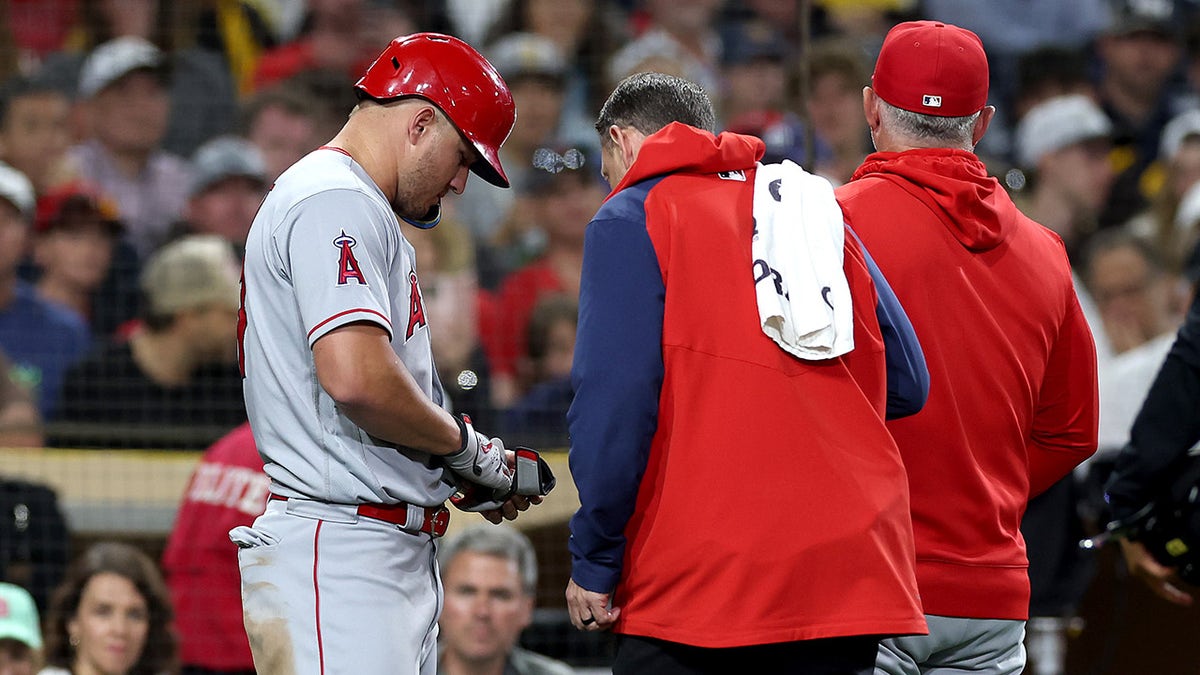 Trainer looks at Mike Trout's hand