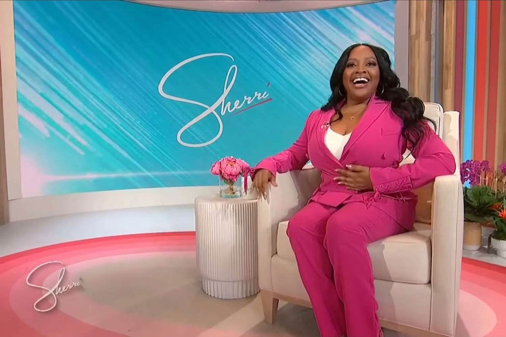 Photo of Sherri Shepherd sitting on the set of her talk show. She's wearing a pink outfit and is smiling broadly.