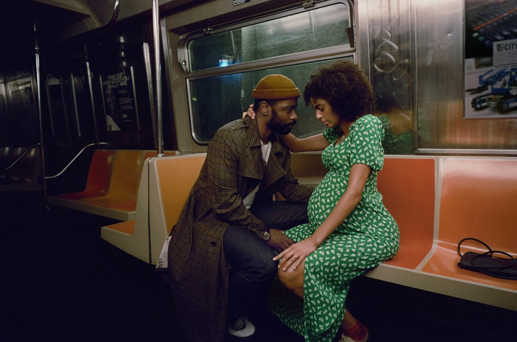 Apollo (LaKeith Stanfield) and Emma (Clark Backo) lean into each other on the subway while she's pregnant. 